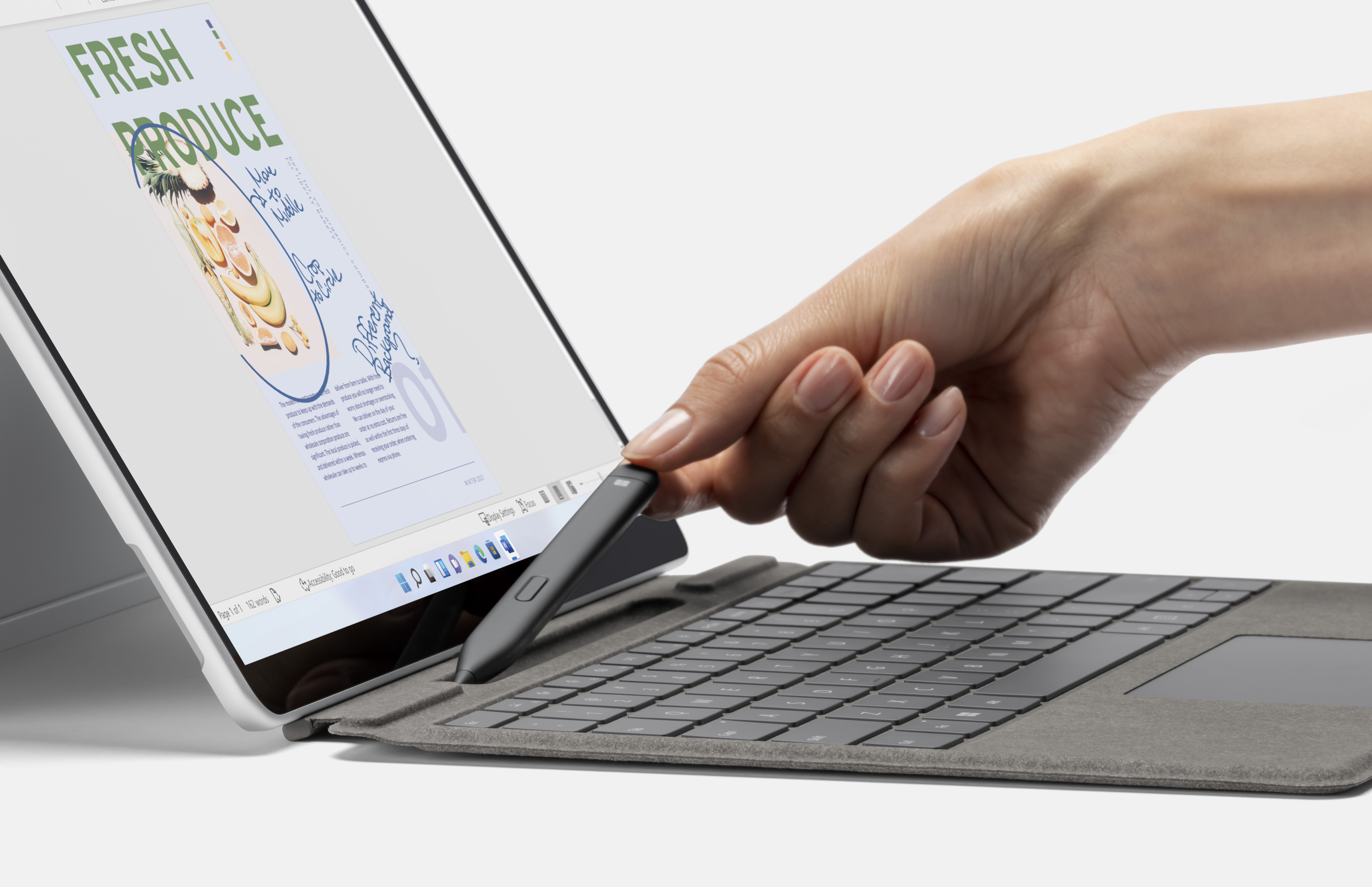 Persona que tiene Microsoft Surface Slim Pen 2 junto a Surface Pro 8 