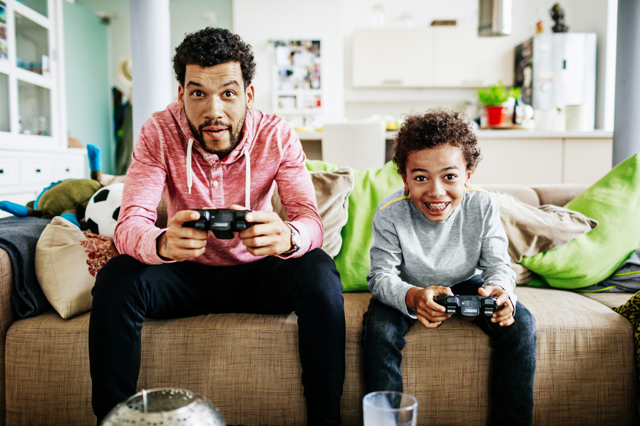 hombre y niño en el sofá sosteniendo controladores de videojuegos viendo la televisión