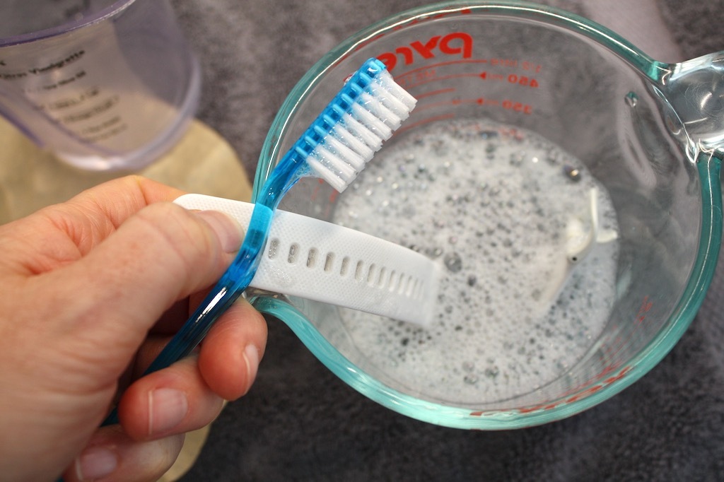 Limpieza de una correa de reloj inteligente de silicona, separada del reloj, con agua, jabón y un cepillo de dientes