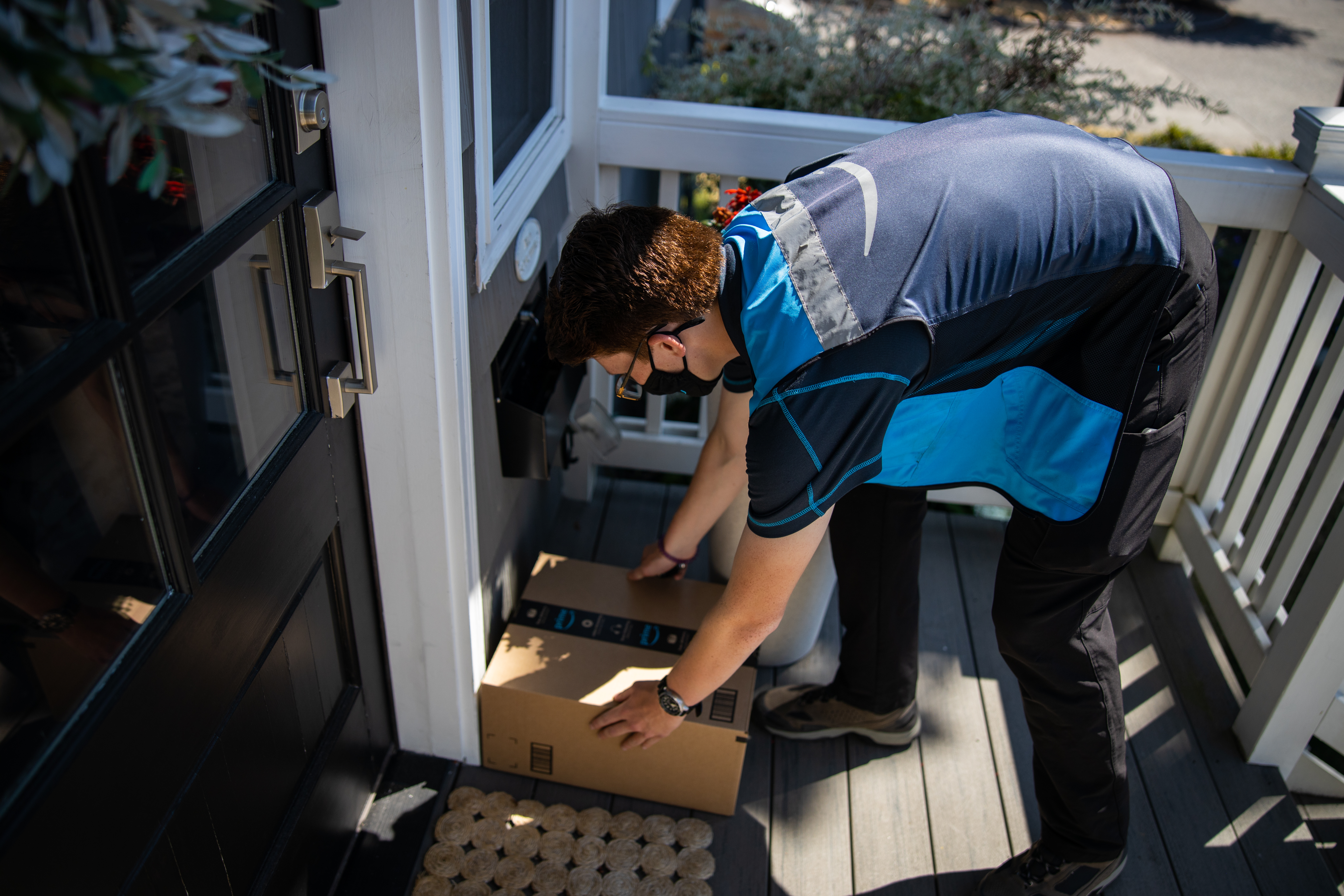 Conductor de entrega de Amazon colocando el paquete en el porche delantero