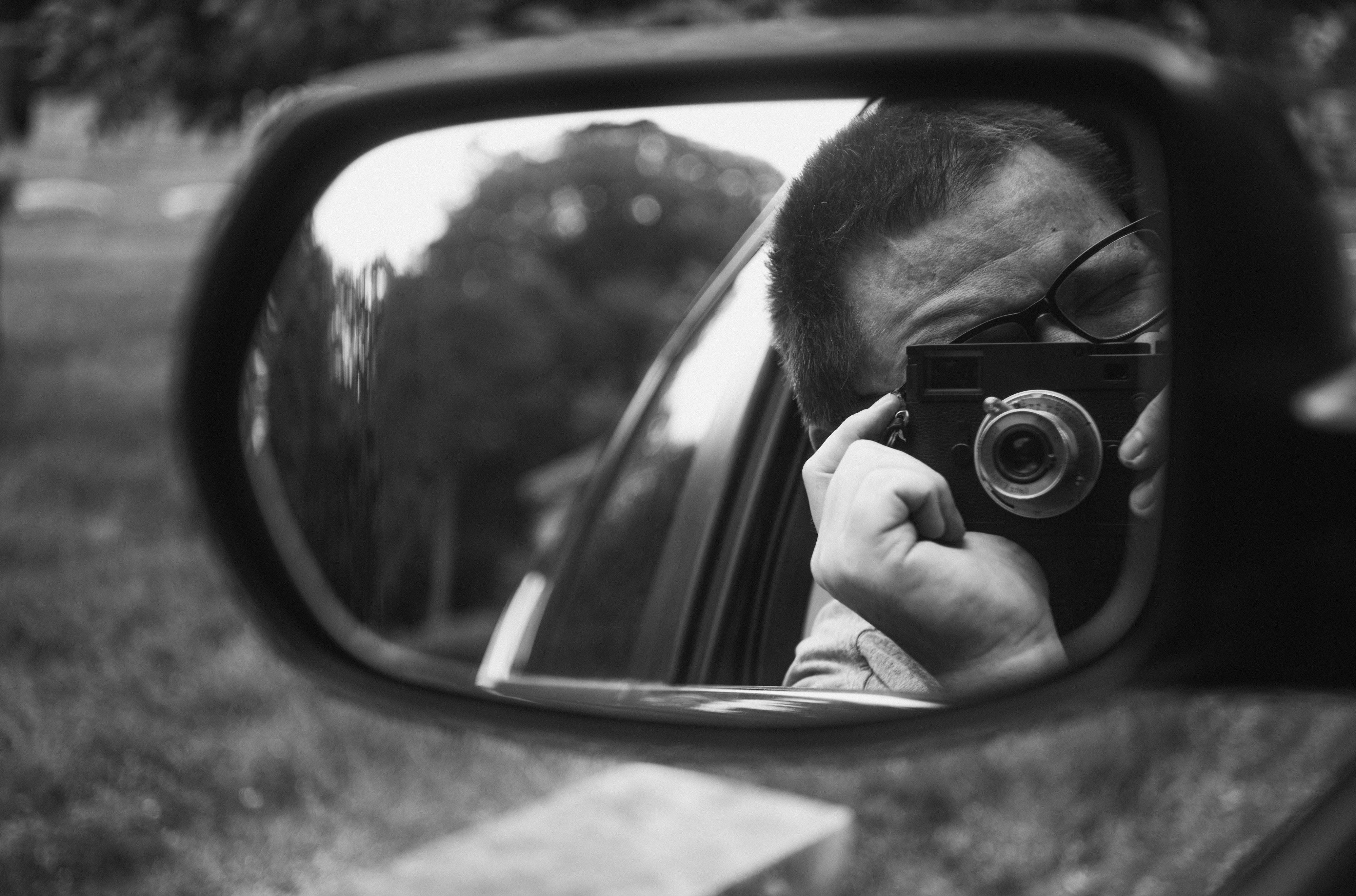 Fotografía en blanco y negro capturada con Leica M10 Monochrom que muestra a la cámara y al fotógrafo en el espejo lateral