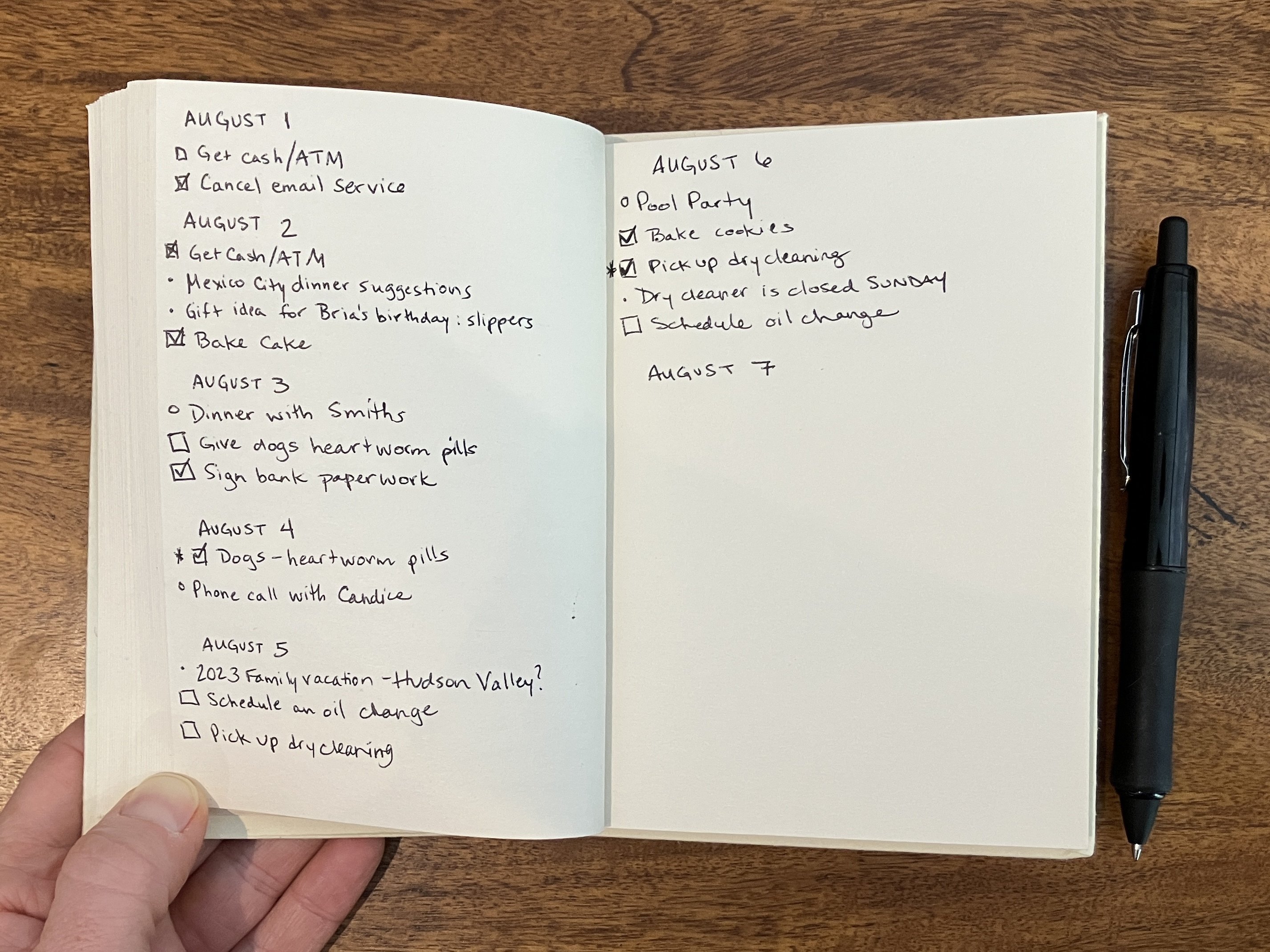 Un cuaderno de papel abierto en una extensión de páginas con cada día del mes escrito y debajo de él tareas, eventos e ideas escritas usando el Método Bullet Journal de marca registrada