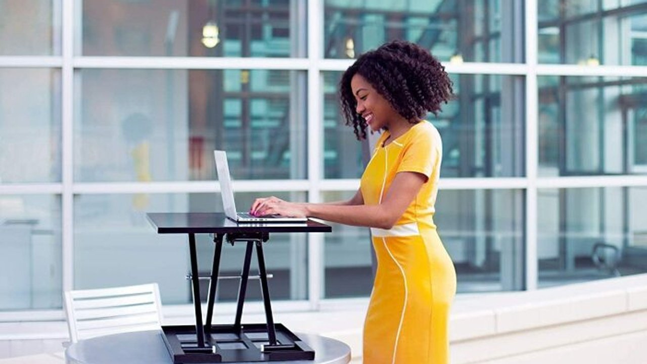 Una mujer que trabaja en una computadora portátil en un escritorio de pie